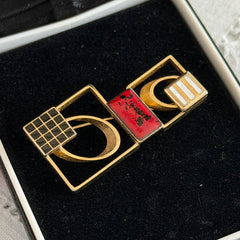 Vintage geometric modernist brooch with red, black, and white enamel in gold‑tone metal.