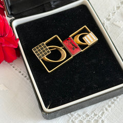 Vintage geometric modernist brooch with red, black, and white enamel in gold‑tone metal.