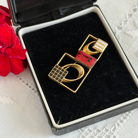Vintage geometric modernist brooch with red, black, and white enamel in gold‑tone metal.