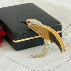 Vintage modernist bird brooch in gold and silver tone with pavé rhinestones and black enamel details.