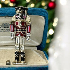 Vintage Monet nutcracker brooch with red and clear rhinestones, black and red enamel, and light gold tone finish, signed on back, holiday-themed costume jewelry in excellent condition