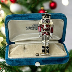 Vintage Monet nutcracker brooch with red and clear rhinestones, black and red enamel, and light gold tone finish, signed on back, holiday-themed costume jewelry in excellent condition