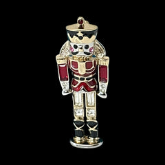 Vintage Monet nutcracker brooch with red and clear rhinestones, black and red enamel, and light gold tone finish, signed on back, holiday-themed costume jewelry in excellent condition