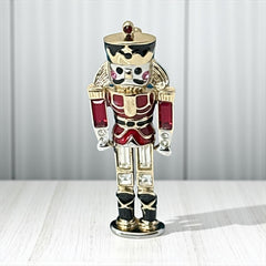 Vintage Monet nutcracker brooch with red and clear rhinestones, black and red enamel, and light gold tone finish, signed on back, holiday-themed costume jewelry in excellent condition