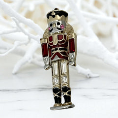 Vintage Monet nutcracker brooch with red and clear rhinestones, black and red enamel, and light gold tone finish, signed on back, holiday-themed costume jewelry in excellent condition