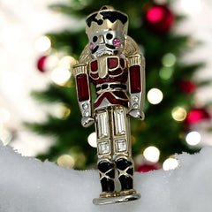 Vintage Monet nutcracker brooch with red and clear rhinestones, black and red enamel, and light gold tone finish, signed on back, holiday-themed costume jewelry in excellent condition