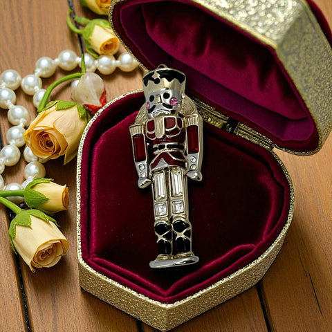 Vintage Monet nutcracker brooch with red and clear rhinestones, black and red enamel, and light gold tone finish, signed on back, holiday-themed costume jewelry in excellent condition