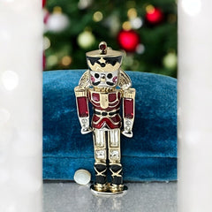 Vintage Monet nutcracker brooch with red and clear rhinestones, black and red enamel, and light gold tone finish, signed on back, holiday-themed costume jewelry in excellent condition