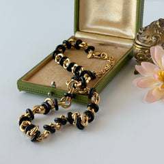 Vintage Monet gold‑tone chain link necklace with black accents, shown in various angles to highlight its adjustable length and signed hangtag.