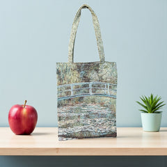 Tapestry tote bag featuring Monet’s Japanese Bridge and Water Lilies, woven in France with soft green, blue, and pink tones; double-sided print with long handles, inspired by Impressionist art.