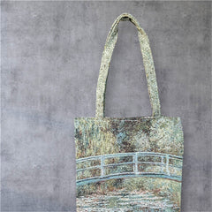 Tapestry tote bag featuring Monet’s Japanese Bridge and Water Lilies, woven in France with soft green, blue, and pink tones; double-sided print with long handles, inspired by Impressionist art.