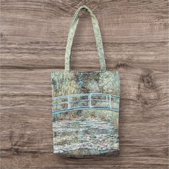 Tapestry tote bag featuring Monet’s Japanese Bridge and Water Lilies, woven in France with soft green, blue, and pink tones; double-sided print with long handles, inspired by Impressionist art.