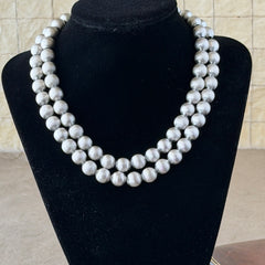 Vintage Monet brushed silver tone two‑strand bead necklace displayed on a black velvet bust and vintage botanical background.