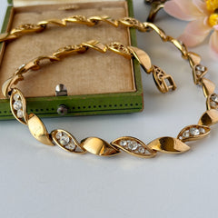 Vintage Monet gold‑tone marquise link necklace with alternating polished and openwork rhinestone links, shown in various angles to highlight its bright finish, signed clasp, and 16½‑inch length.
