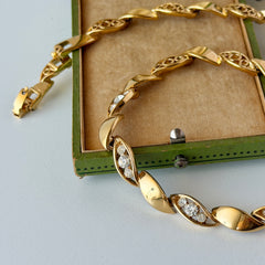 Vintage Monet gold‑tone marquise link necklace with alternating polished and openwork rhinestone links, shown in various angles to highlight its bright finish, signed clasp, and 16½‑inch length.