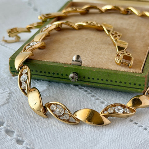 Vintage Monet gold‑tone marquise link necklace with alternating polished and openwork rhinestone links, shown in various angles to highlight its bright finish, signed clasp, and 16½‑inch length.