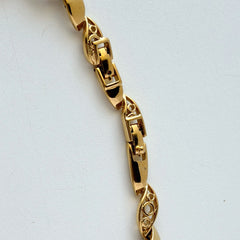 Vintage Monet gold‑tone marquise link necklace with alternating polished and openwork rhinestone links, shown in various angles to highlight its bright finish, signed clasp, and 16½‑inch length.