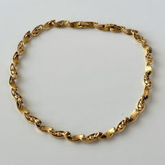Vintage Monet gold‑tone marquise link necklace with alternating polished and openwork rhinestone links, shown in various angles to highlight its bright finish, signed clasp, and 16½‑inch length.