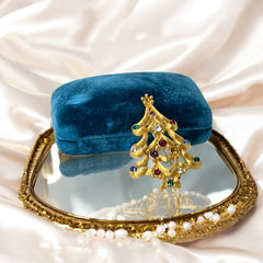 Vintage 1980s Monet Christmas tree brooch in textured gold tone with multicolor rhinestones, featuring curved branches, star topper, and signed back clasp—shown front and back to highlight design detail and maker’s mark.