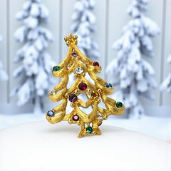 Vintage 1980s Monet Christmas tree brooch in textured gold tone with multicolor rhinestones, featuring curved branches, star topper, and signed back clasp—shown front and back to highlight design detail and maker’s mark.