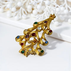 Vintage 1980s Monet Christmas tree brooch in textured gold tone with multicolor rhinestones, featuring curved branches, star topper, and signed back clasp—shown front and back to highlight design detail and maker’s mark.