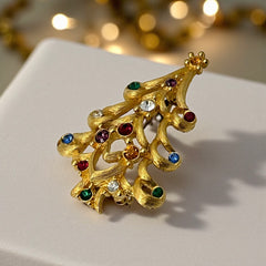 Vintage 1980s Monet Christmas tree brooch in textured gold tone with multicolor rhinestones, featuring curved branches, star topper, and signed back clasp—shown front and back to highlight design detail and maker’s mark.