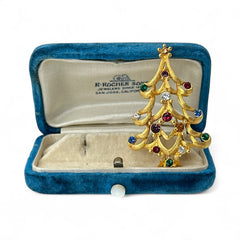 Vintage 1980s Monet Christmas tree brooch in textured gold tone with multicolor rhinestones, featuring curved branches, star topper, and signed back clasp—shown front and back to highlight design detail and maker’s mark.