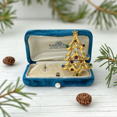 Vintage 1980s Monet Christmas tree brooch in textured gold tone with multicolor rhinestones, featuring curved branches, star topper, and signed back clasp—shown front and back to highlight design detail and maker’s mark.