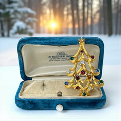 Vintage 1980s Monet Christmas tree brooch in textured gold tone with multicolor rhinestones, featuring curved branches, star topper, and signed back clasp—shown front and back to highlight design detail and maker’s mark.