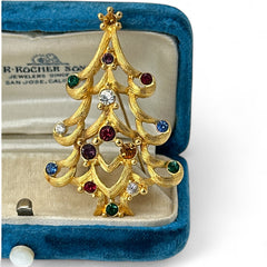 Vintage 1980s Monet Christmas tree brooch in textured gold tone with multicolor rhinestones, featuring curved branches, star topper, and signed back clasp—shown front and back to highlight design detail and maker’s mark.