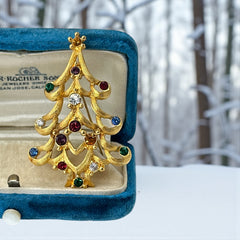 Vintage 1980s Monet Christmas tree brooch in textured gold tone with multicolor rhinestones, featuring curved branches, star topper, and signed back clasp—shown front and back to highlight design detail and maker’s mark.