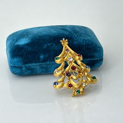 Vintage 1980s Monet Christmas tree brooch in textured gold tone with multicolor rhinestones, featuring curved branches, star topper, and signed back clasp—shown front and back to highlight design detail and maker’s mark.