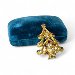 Vintage 1980s Monet Christmas tree brooch in textured gold tone with multicolor rhinestones, featuring curved branches, star topper, and signed back clasp—shown front and back to highlight design detail and maker’s mark.