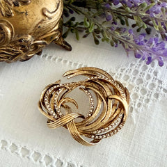 Vintage Monet textured gold tone swirl brooch with pave rhinestones, 1960s signed piece.