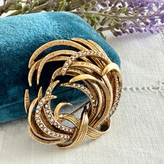 Vintage Monet textured gold tone swirl brooch with pave rhinestones, 1960s signed piece.
