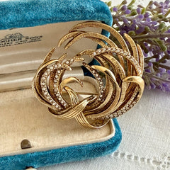 Vintage Monet textured gold tone swirl brooch with pave rhinestones, 1960s signed piece.