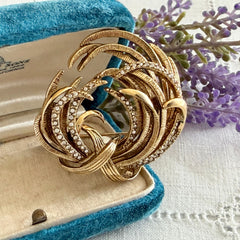 Vintage Monet textured gold tone swirl brooch with pave rhinestones, 1960s signed piece.