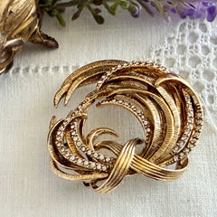 Vintage Monet textured gold tone swirl brooch with pave rhinestones, 1960s signed piece.