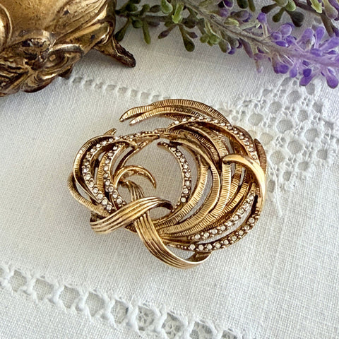 Vintage Monet textured gold tone swirl brooch with pave rhinestones, 1960s signed piece.