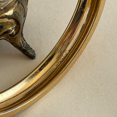 Vintage Monet gold‑tone minimalist bangle bracelet with a smooth polished finish, shown in close‑up on a neutral background.