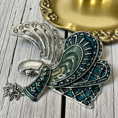 Vintage Monet angel brooch in silver tone metal with teal and light green enamel robe, clear rhinestone wings, and raised star detail; signed Monet on back.