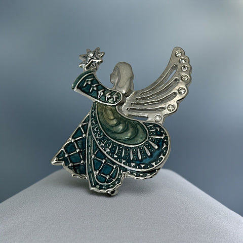 Vintage Monet angel brooch in silver tone metal with teal and light green enamel robe, clear rhinestone wings, and raised star detail; signed Monet on back.