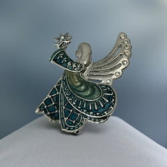 Vintage Monet angel brooch in silver tone metal with teal and light green enamel robe, clear rhinestone wings, and raised star detail; signed Monet on back.