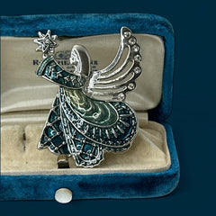 Vintage Monet angel brooch in silver tone metal with teal and light green enamel robe, clear rhinestone wings, and raised star detail; signed Monet on back.