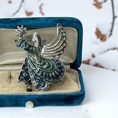 Vintage Monet angel brooch in silver tone metal with teal and light green enamel robe, clear rhinestone wings, and raised star detail; signed Monet on back.