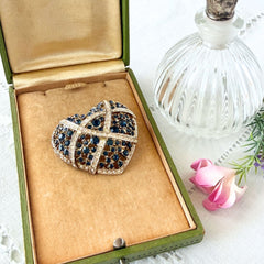 Vintage heart brooch with Montana sapphire and clear rhinestones in silver‑tone metal with gold wash, displayed on lace with a green book and pink flower