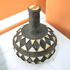 Vintage Moroccan pottery vase from the 1970s/80s, featuring a large clay body with ornate metal inlays, an antiqued bronze/brass finish, and three geometric rings of camel bone triangle patterns. Includes an original metal lid, reflecting its historic use for storing and transporting liquids. In very good vintage condition, showcasing intricate craftsmanship and cultural heritage.