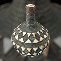 Vintage Moroccan pottery vase from the 1970s/80s, featuring a large clay body with ornate metal inlays, an antiqued bronze/brass finish, and three geometric rings of camel bone triangle patterns. Includes an original metal lid, reflecting its historic use for storing and transporting liquids. In very good vintage condition, showcasing intricate craftsmanship and cultural heritage.