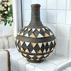 Vintage Moroccan pottery vase from the 1970s/80s, featuring a large clay body with ornate metal inlays, an antiqued bronze/brass finish, and three geometric rings of camel bone triangle patterns. Includes an original metal lid, reflecting its historic use for storing and transporting liquids. In very good vintage condition, showcasing intricate craftsmanship and cultural heritage.