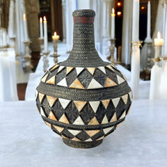 Vintage Moroccan pottery vase from the 1970s/80s, featuring a large clay body with ornate metal inlays, an antiqued bronze/brass finish, and three geometric rings of camel bone triangle patterns. Includes an original metal lid, reflecting its historic use for storing and transporting liquids. In very good vintage condition, showcasing intricate craftsmanship and cultural heritage.
